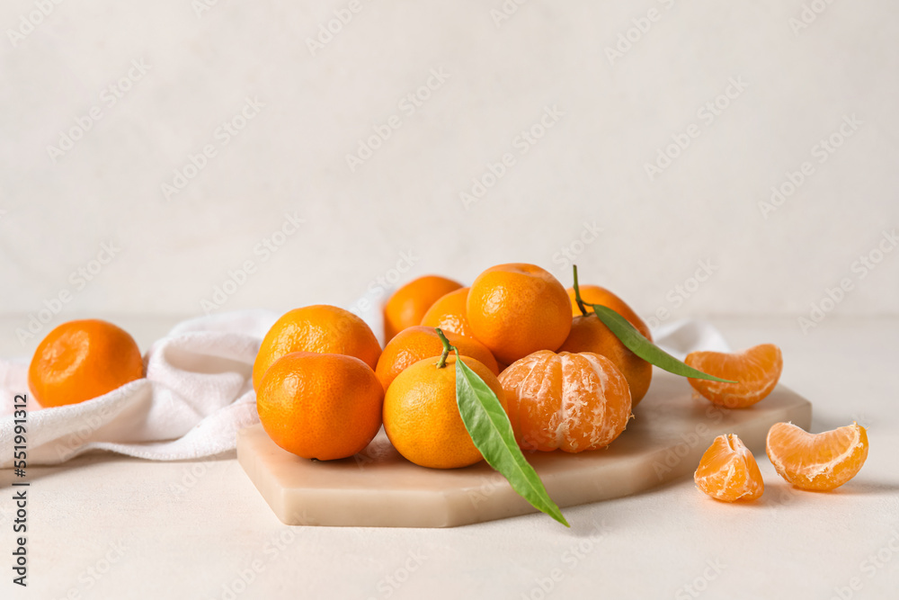 Board with fresh ripe tangerines on light background