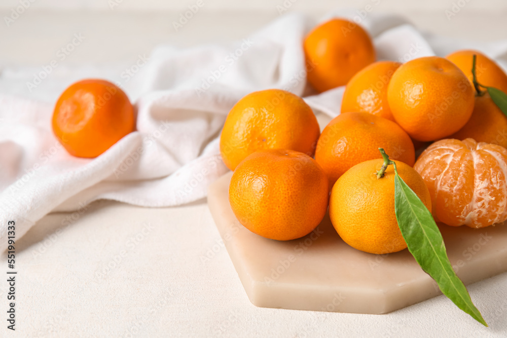 Board with fresh ripe tangerines on light background