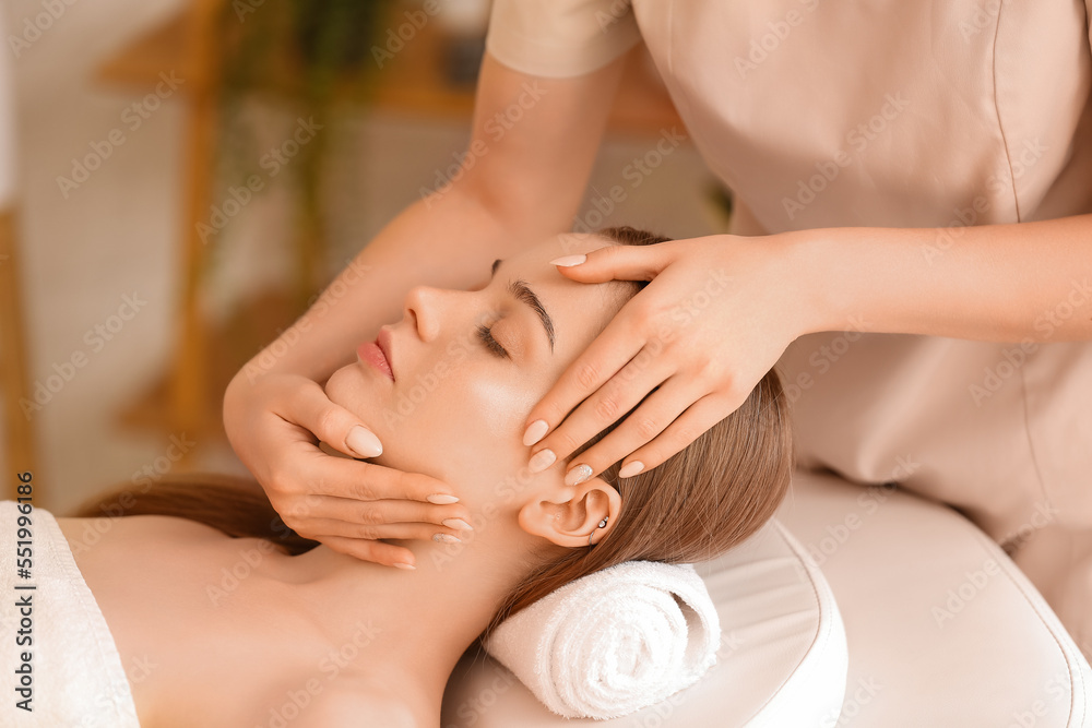 Pretty young woman receiving face massage in beauty salon