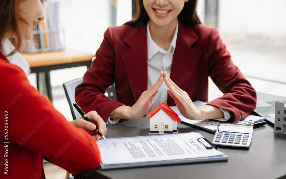 Female real estate agent is use hands to protect red roof for the concept of real estate investment 