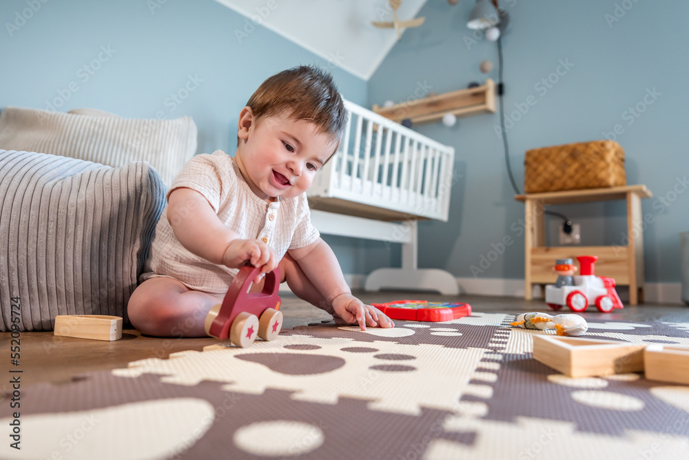 Little boy playing his toys on floor in child room