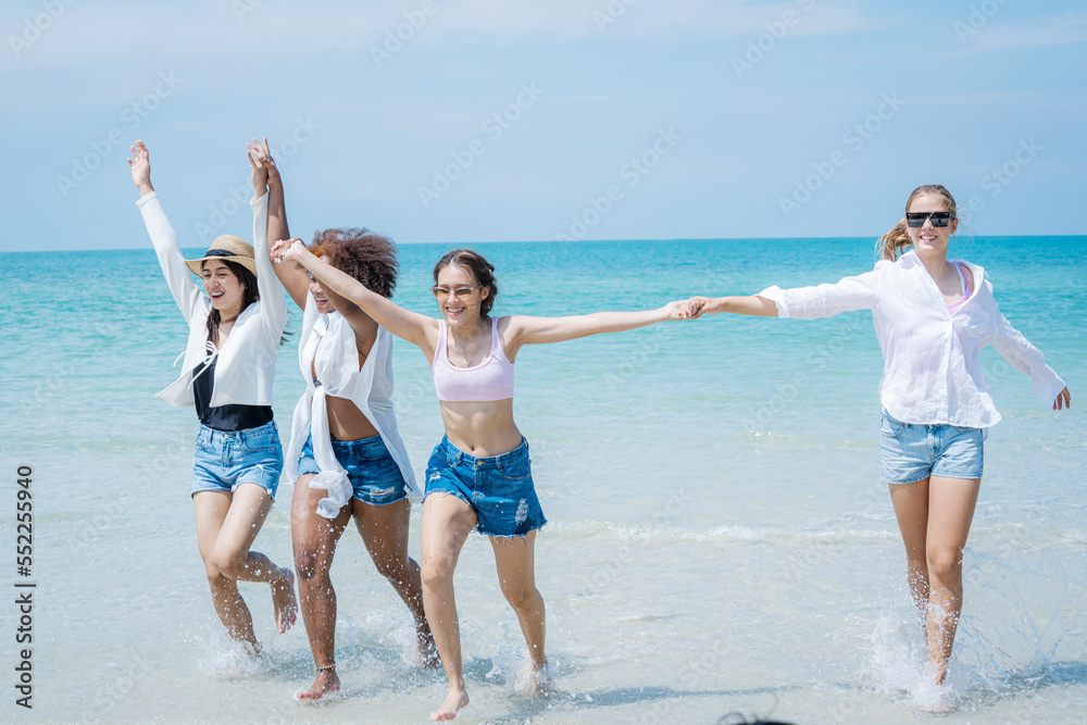 Group of young woman having fun playing on the beach together. Attractive woman friends feeling happ