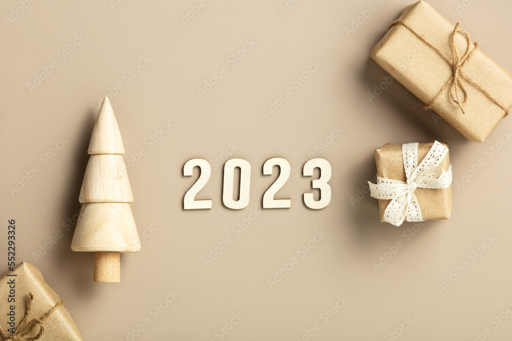 Natural color Christmas gift boxes and wooden Christmas tree on beige background, eco friendly trend