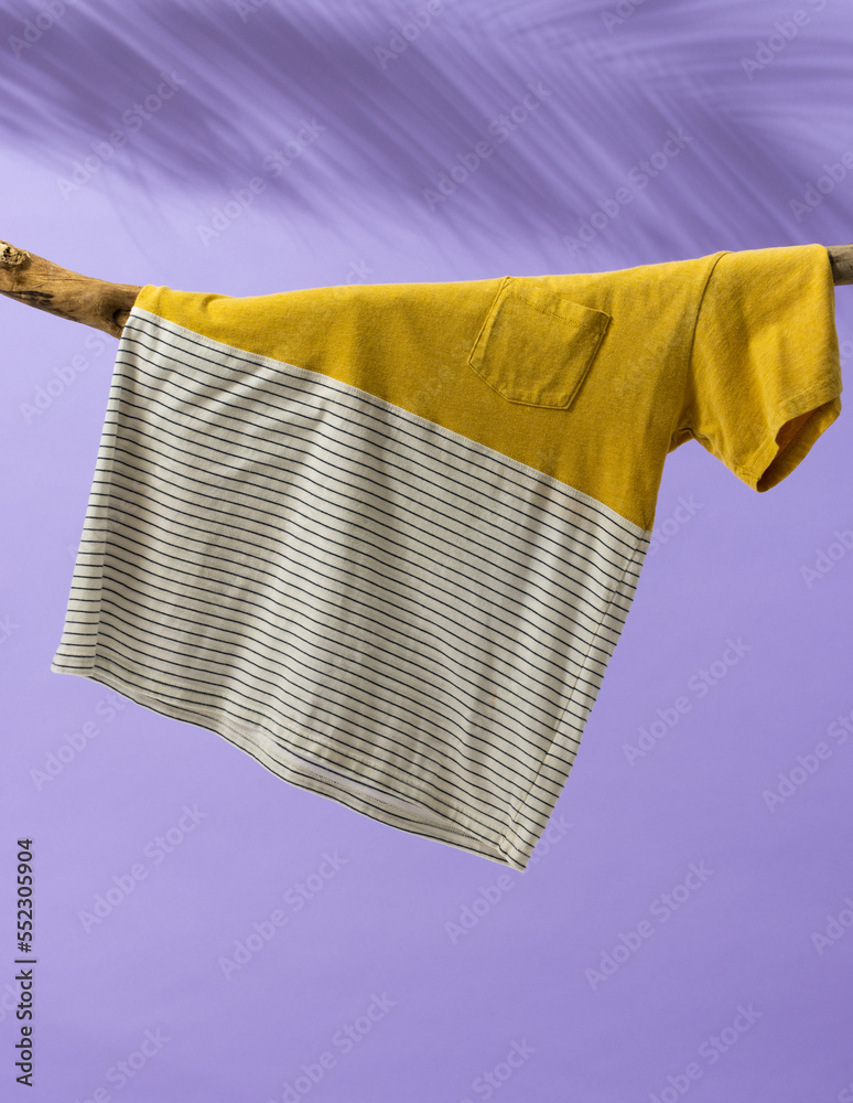 Tshirt hanging on branch and copy space on purple background