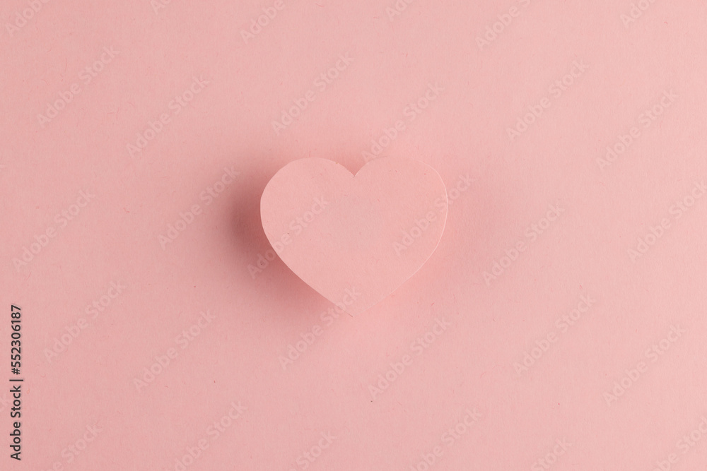 Elevated pink heart shape and shadow on pink background with copy space