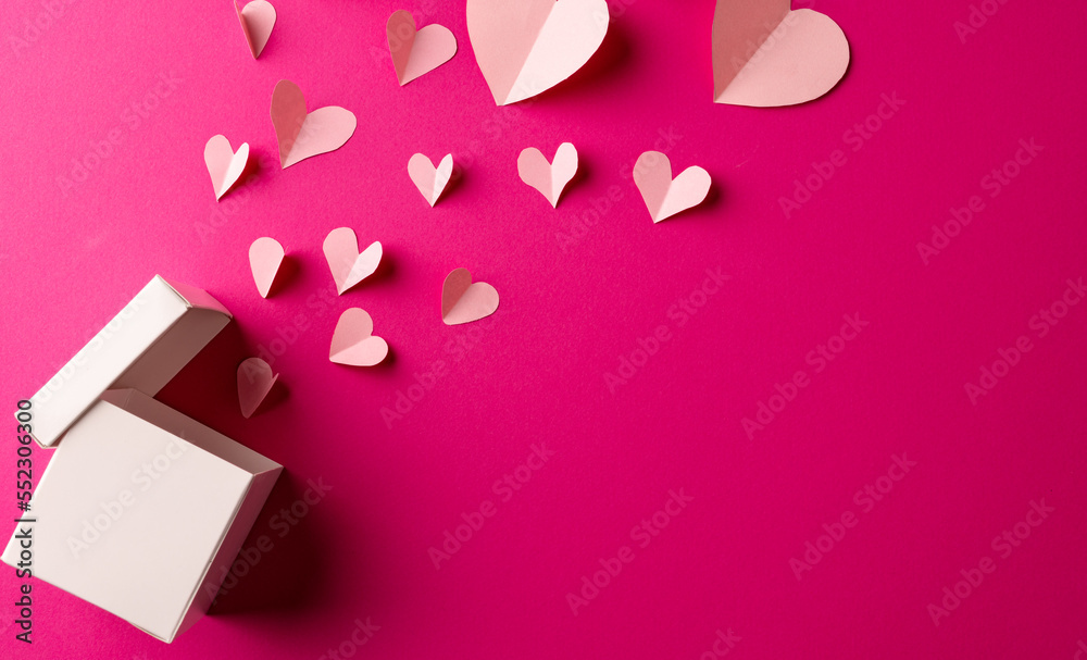 Open white gift box releasing white hearts on pink background with copy space