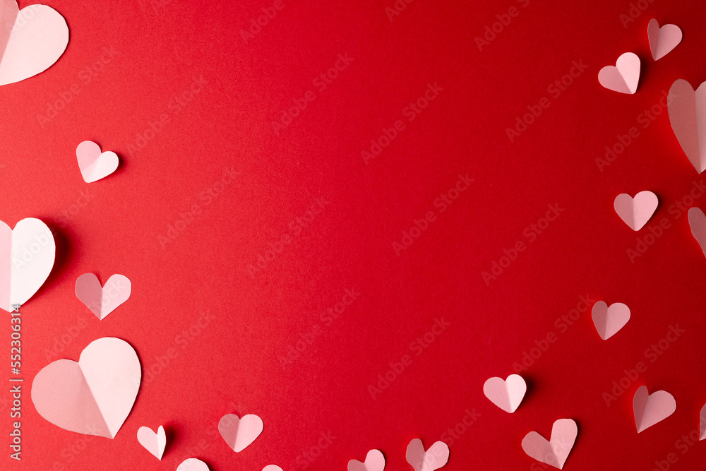 White paper heart shapes, on red background with central copy space