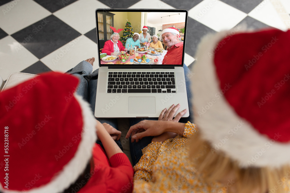 Caucasian mother and daughter having christmas video call with diverse people