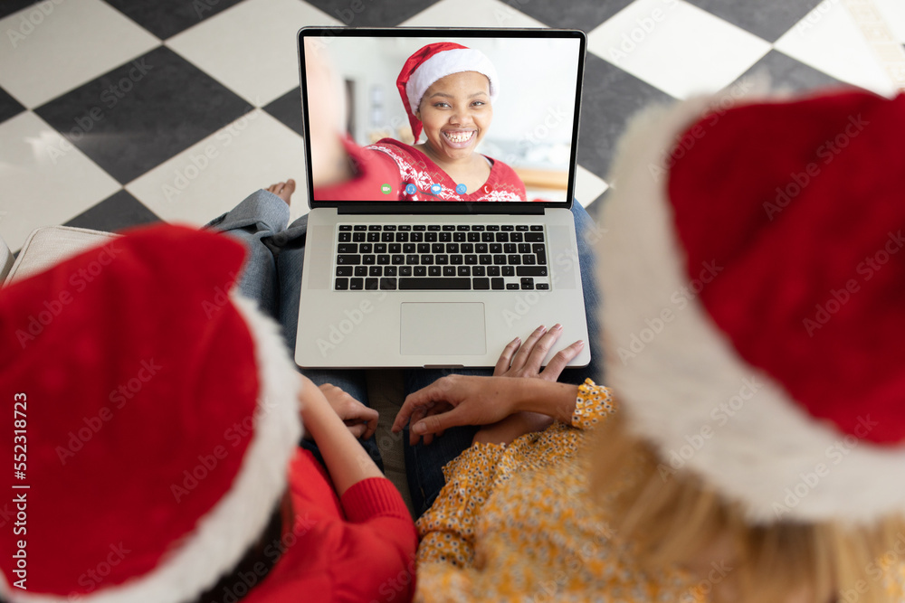 Caucasian mother and daughter having christmas video call with african american woman