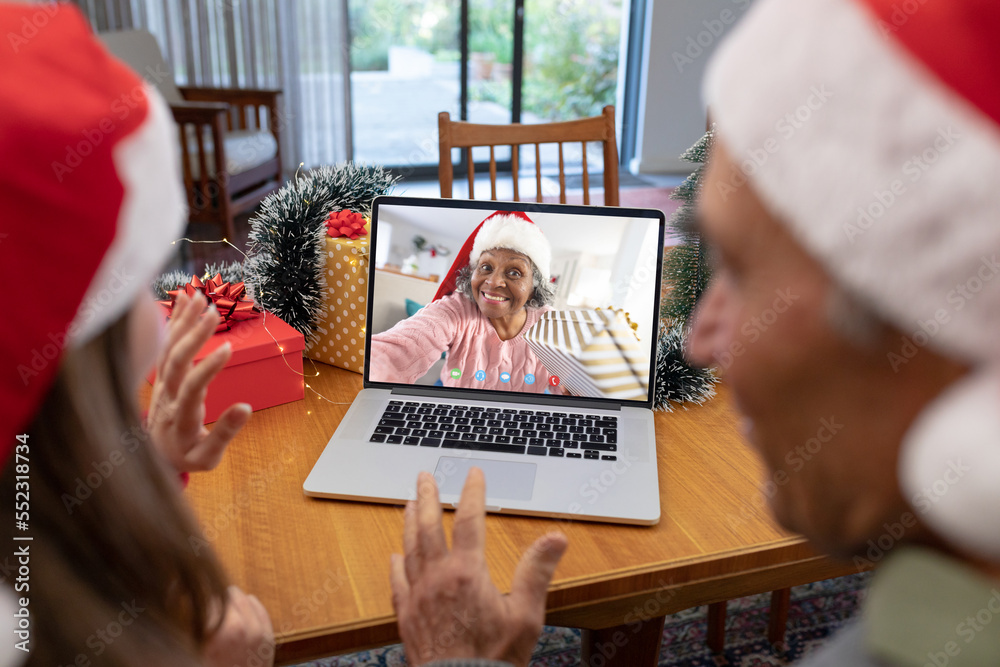 Caucasian father and daughter having christmas video call with senior african american woman