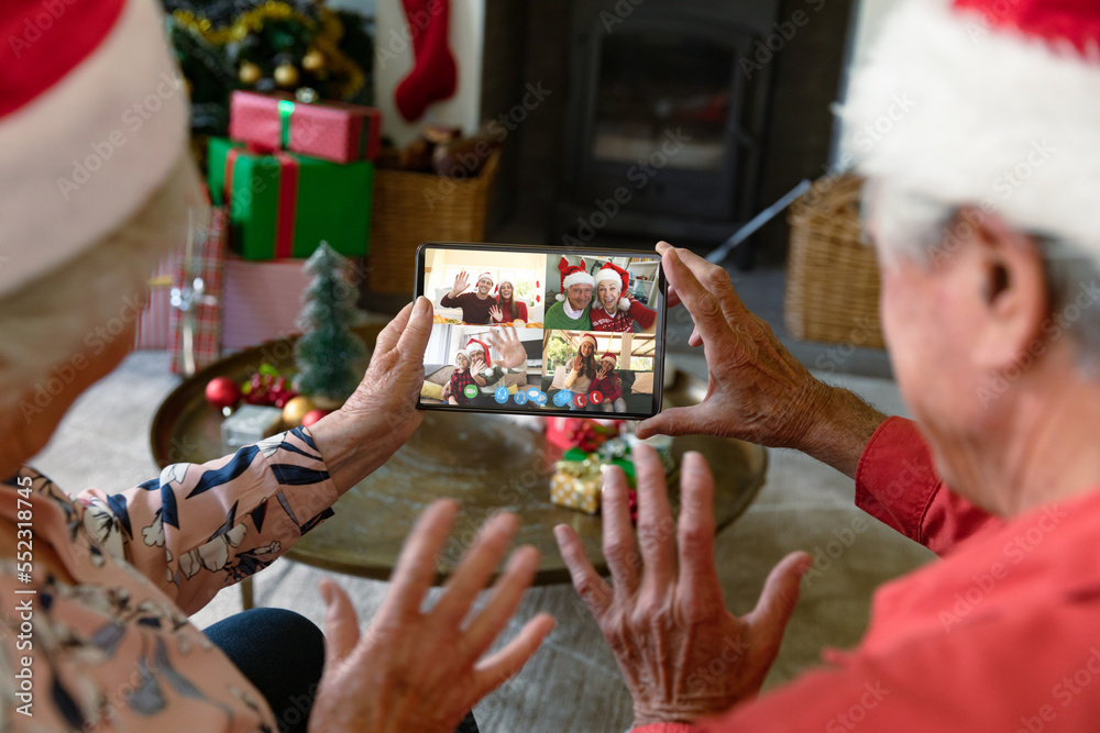 Senior caucasian couple having christmas video call with diverse people