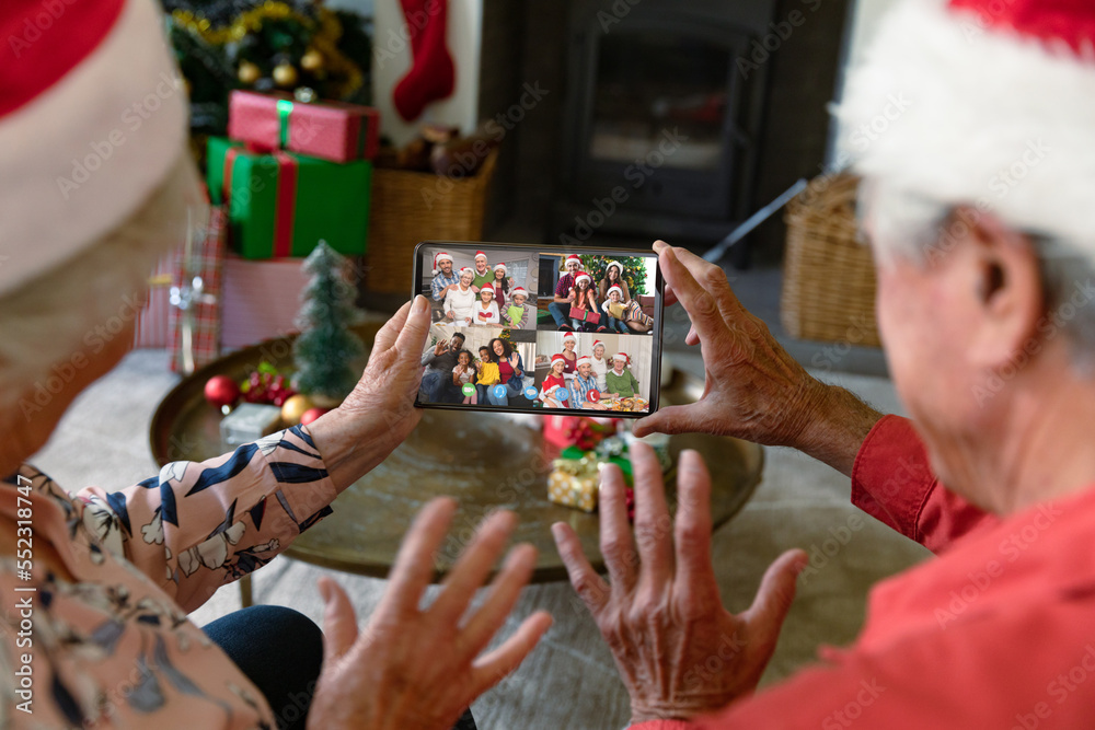 Senior caucasian couple having christmas video call with diverse people