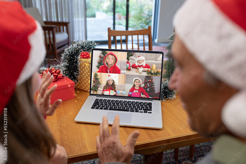 Caucasian father and daughter in santa hats on christmas laptop video call with caucasian children