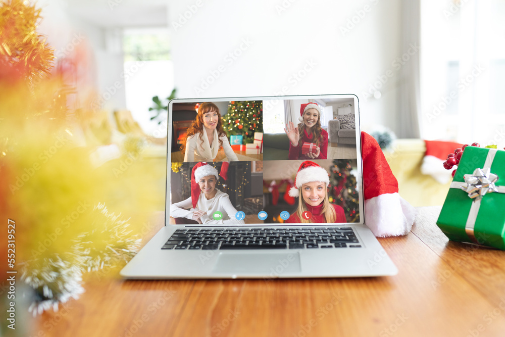 Happy caucasian female friends having christmas laptop video call