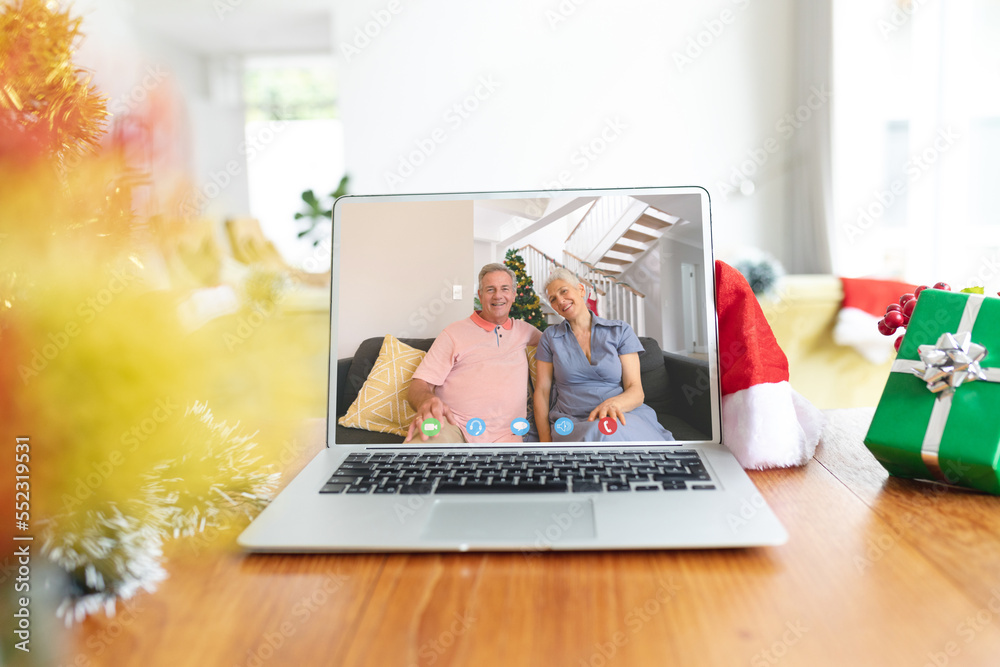 Happy caucasian couple having christmas laptop video call on table