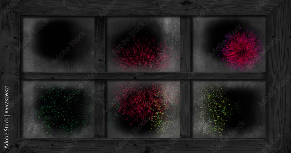 Image of window with colourful christmas and new year fireworks exploding in night sky