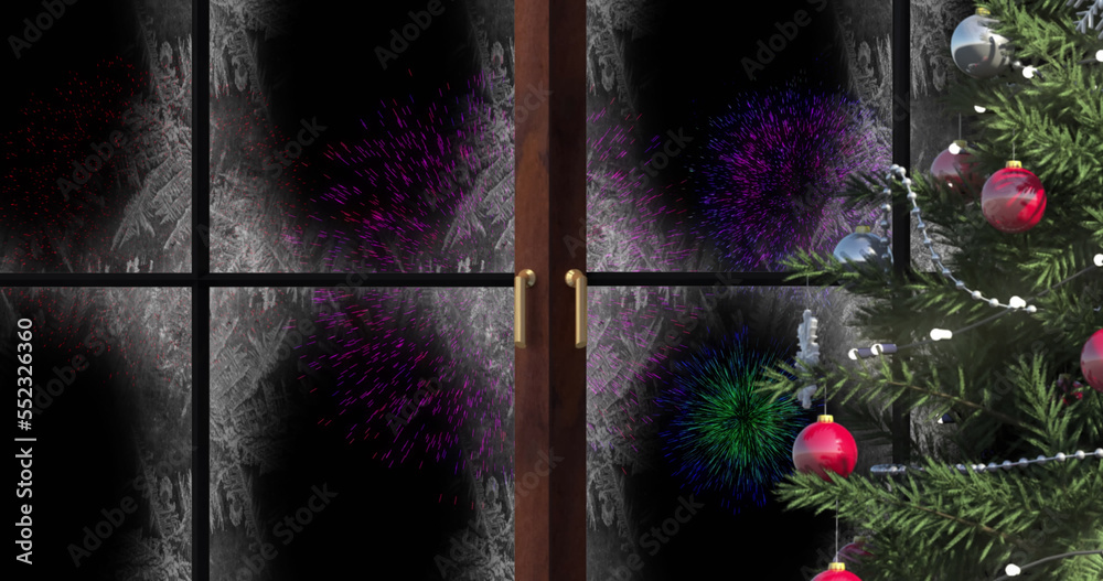 Image of window with snow and christmas tree and fireworks in night sky