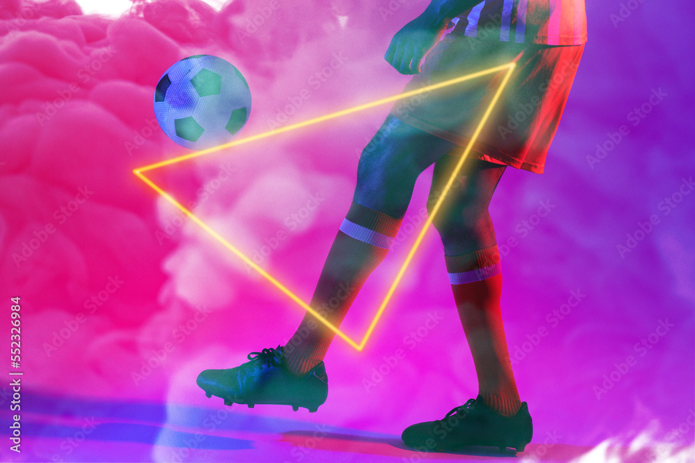 Low section of male player kicking ball with illuminated triangular shape against smoke, copy space