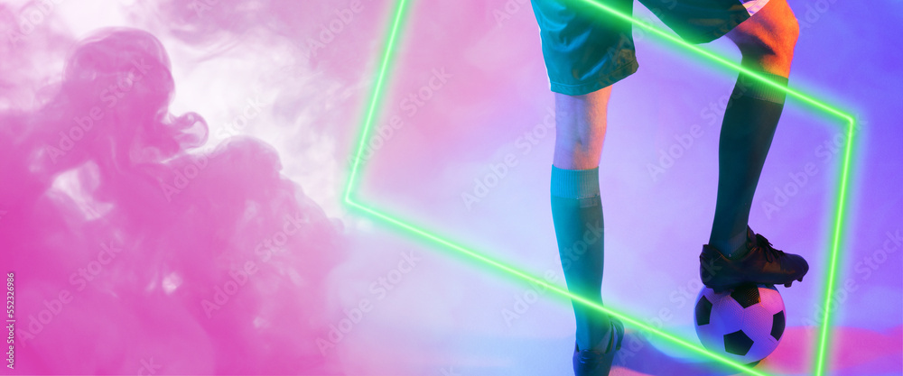 Low section of caucasian male player with leg on ball over illuminated rectangle shape against smoke