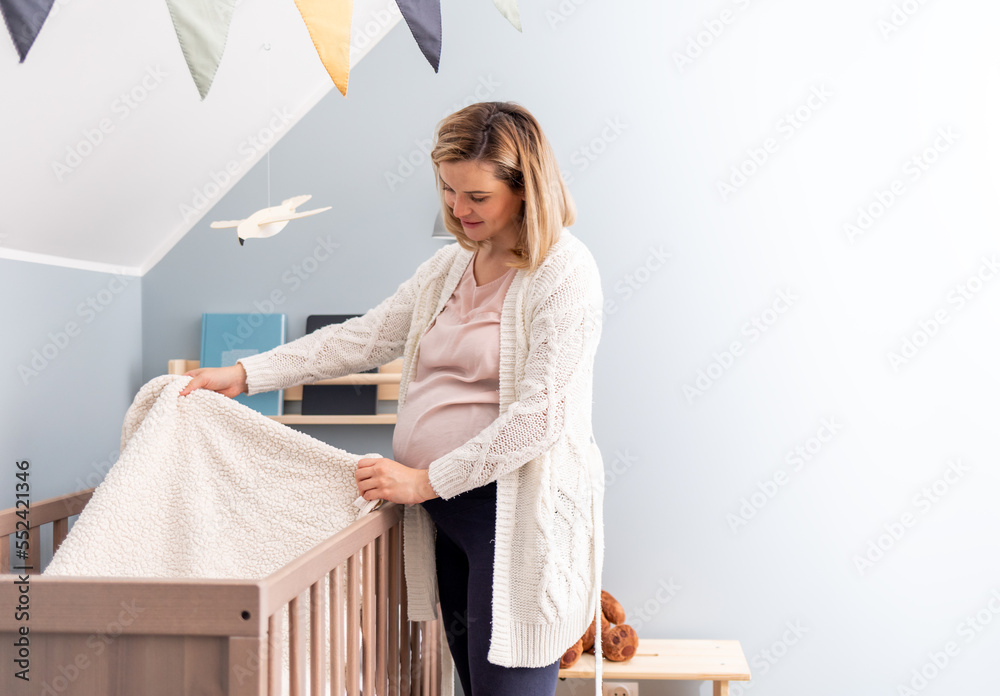 Pregnant woman preparing crib for expected newborn baby