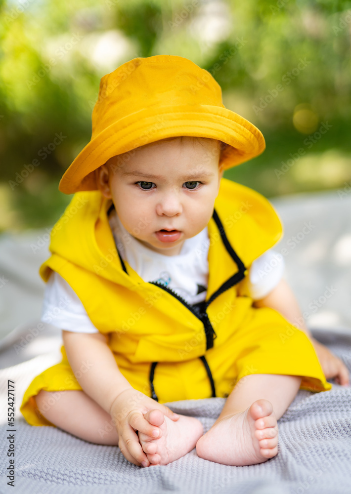 Little baby boy sitting up on a blanket in the park. Outdoor fun for children.