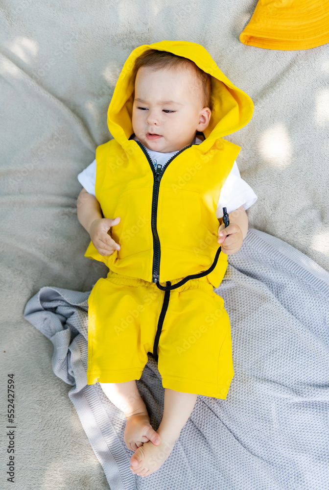 Cute little boy lying on a blanket in the park. Outdoor fun for children.