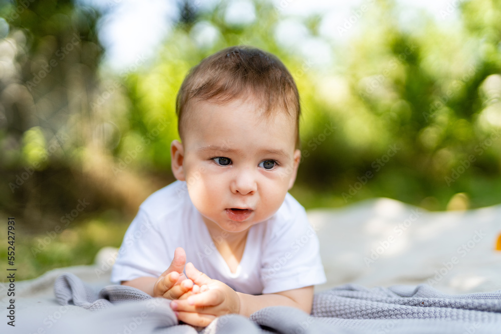 小男婴在公园里坐在毯子上。孩子们在户外玩得很开心。