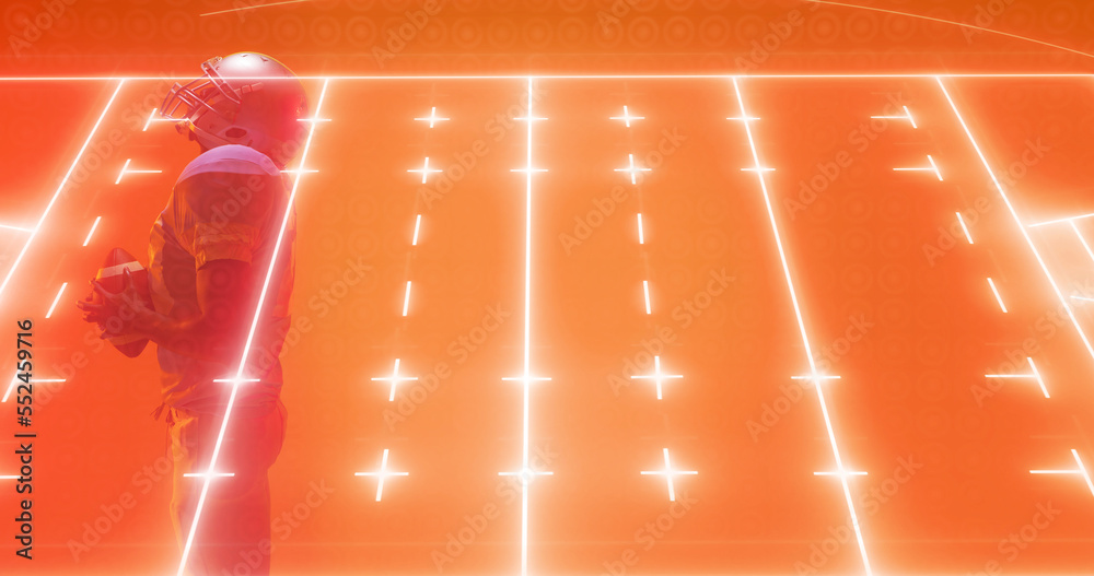 Composite of illuminated american football field over male player standing on orange background