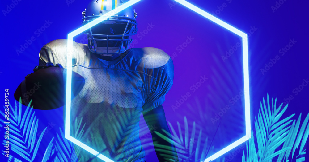 American football player holding ball by illuminated hexagon shape and plants on blue background