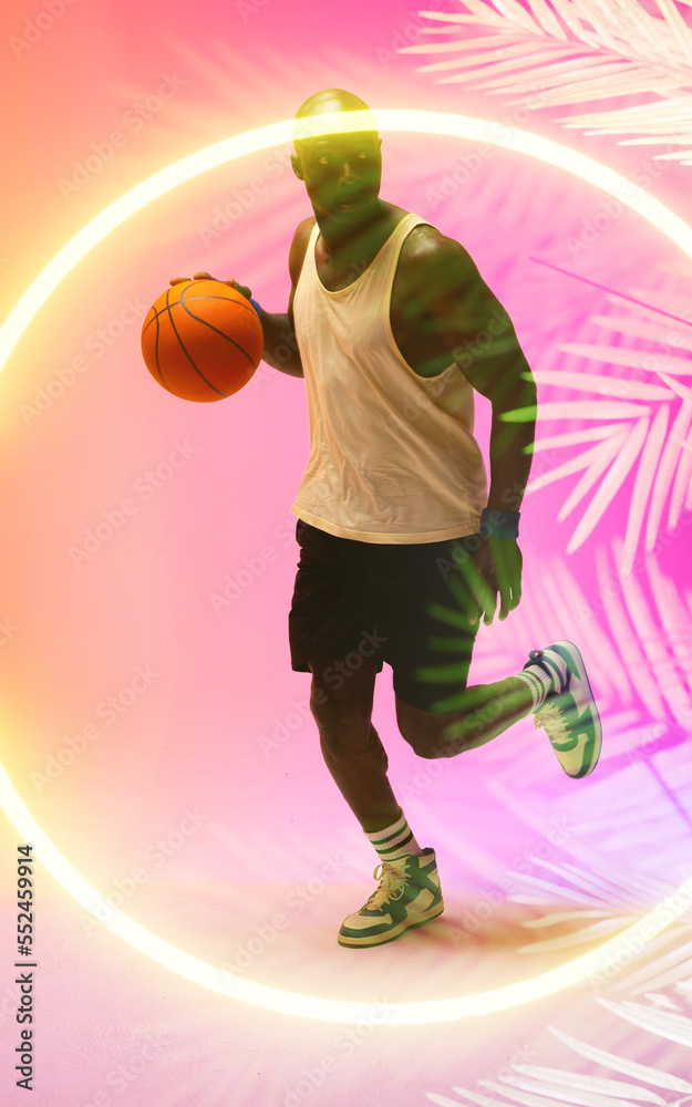 African american basketball player dribbling ball and running by circle and plants