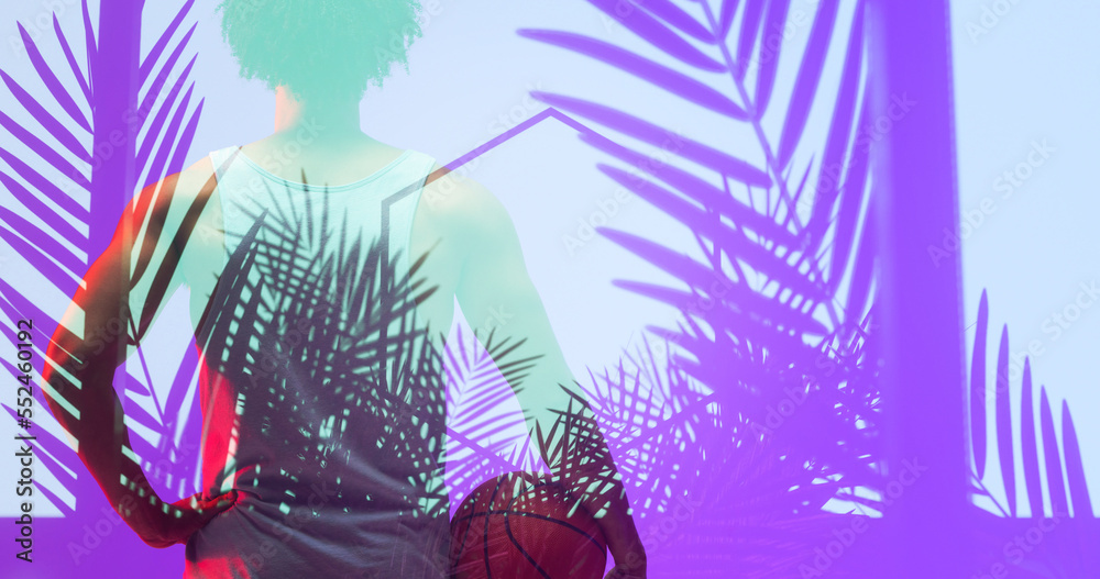 Rear view of biracial basketball player with ball standing over illuminated hexagon and plants