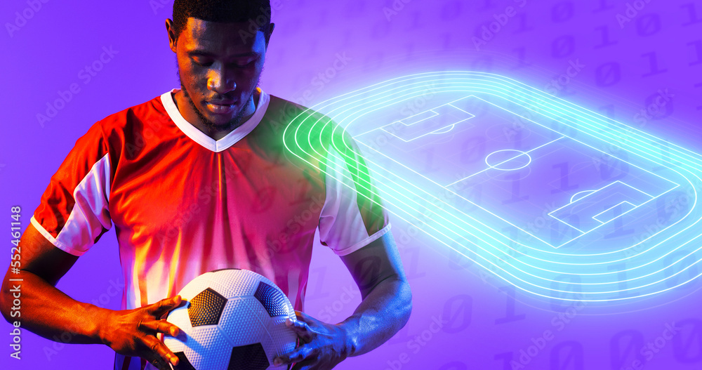 African american male player holding ball by illuminated soccer field over binary codes