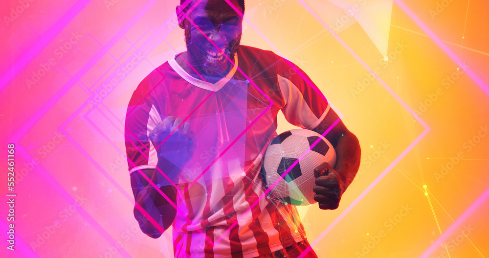 Cheerful african american male soccer player with ball shaking fist over illuminated squares