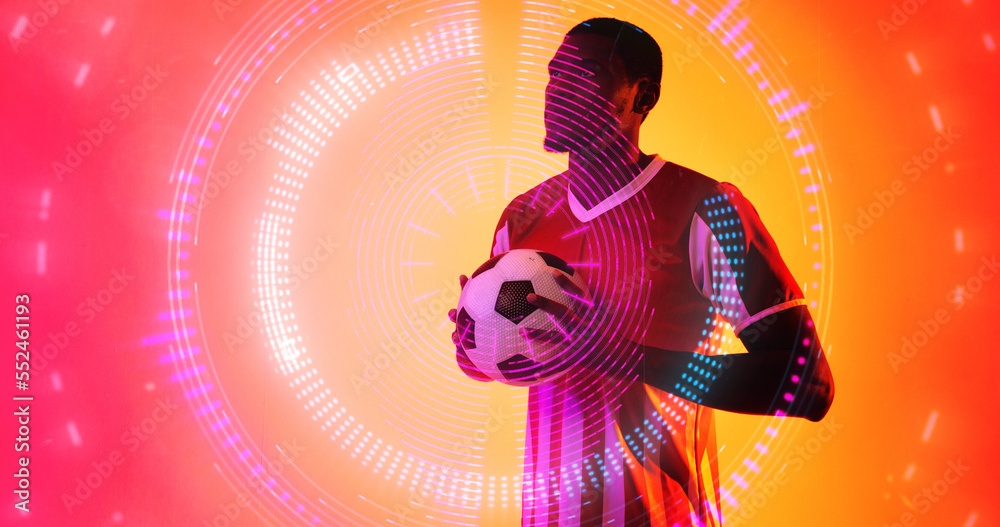 Illuminated circles over african american male player holding soccer ball on colored background