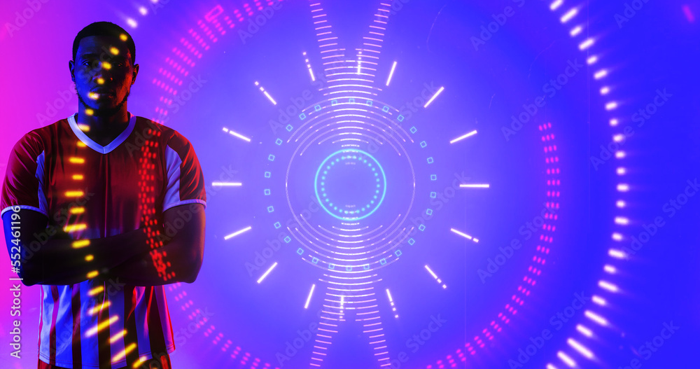 Illuminated circular pattern over portrait of african american male soccer player with arms crossed