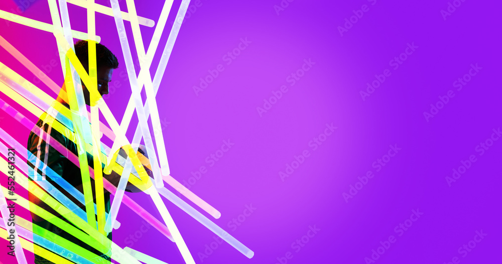 Caucasian young sportsman with colorful neon design over purple background, copy space