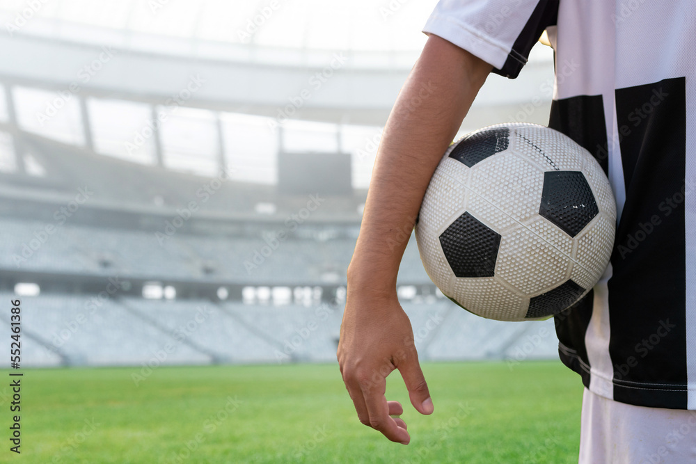 Midsection of player with soccer ball in stadium during sunny day, copy space