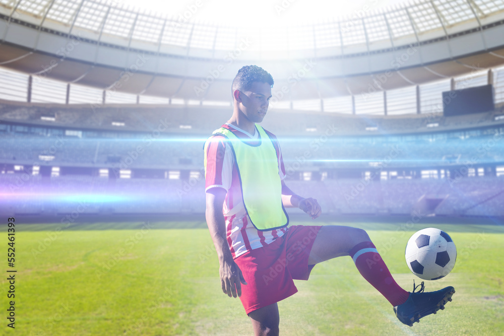 Biracial young soccer player practicing with ball in stadium, copy space