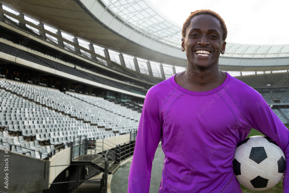 Portrait of happy african american young soccer player with ball in stadium, copy space