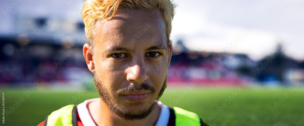 Close-up portrait of serious biracial young male soccer player at stadium, copy space