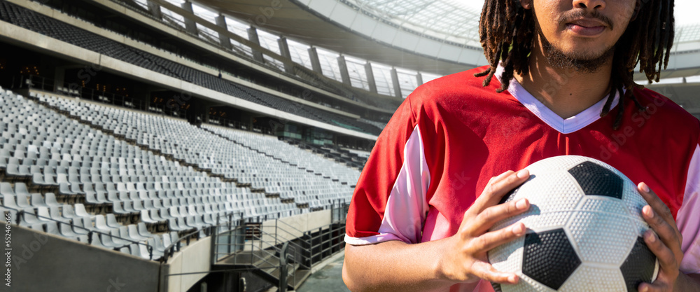 Midsection of african american young male soccer player with ball at stadium, copy space