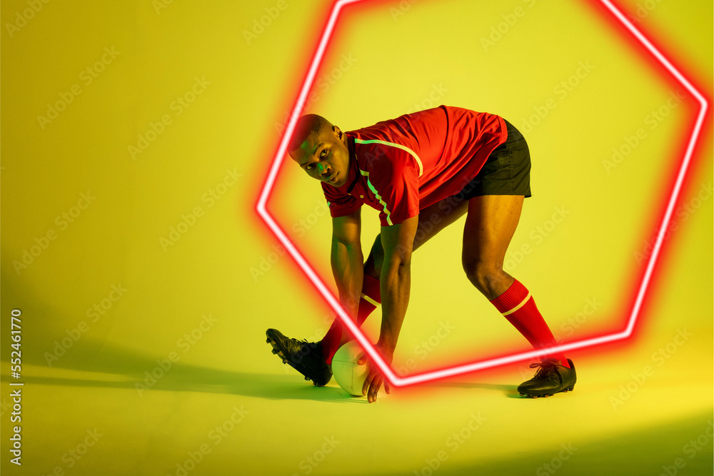 Hexagon neon over african american young rugby player playing against yellow background