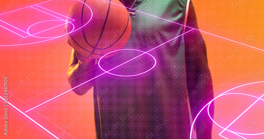 Neon basketball court and midsection of african american player with ball against brown background