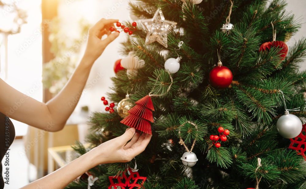 Merry Christmas! Hands Hands opening christmas gift with red bow on background of christmas tree wit