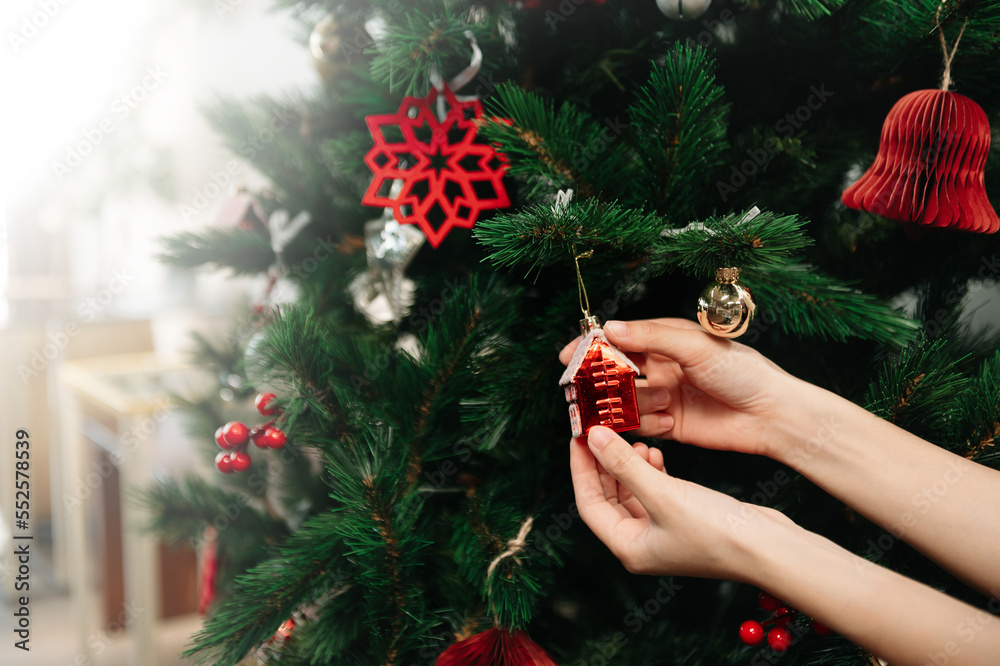 Young womans hand decorating Christmas tree indoors. New year celebration..