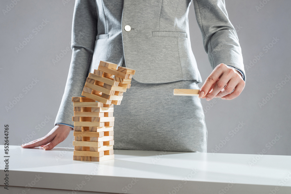 Businesswoman removing wooden block from tower