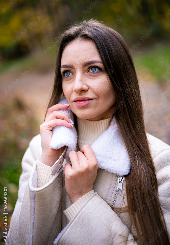 Portrait of elegant young lady in warm coat. Attractive stylish female model in nature.