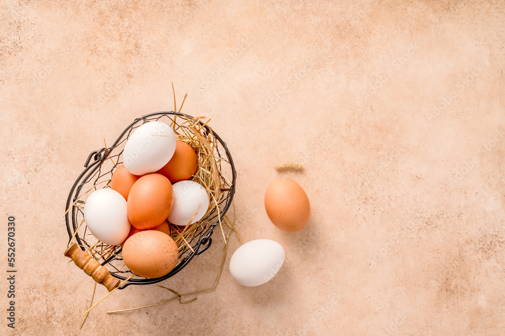 Eggs in metallic basket on beige background. Top view of raw brown eggs and white eggs with copy spa