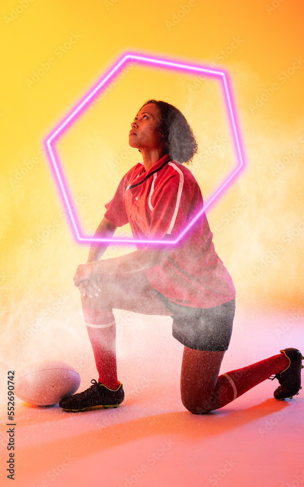 Composite of biracial female rugby player kneeling over illuminated hexagon on colored background