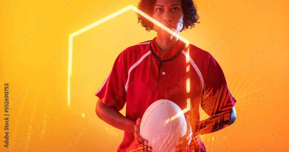 Confident biracial female player with ball and illuminated hexagon and plants on yellow background